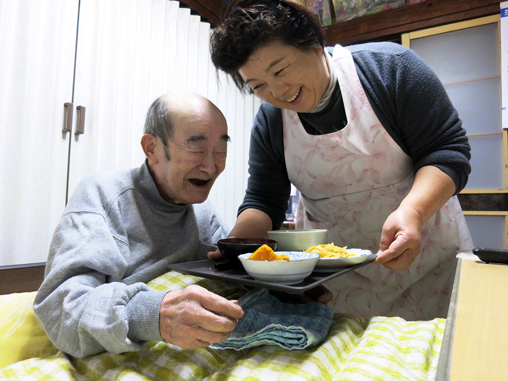 美土里荘訪問介護事業所:ホームヘルパーによる食事介護を受け笑顔の利用者